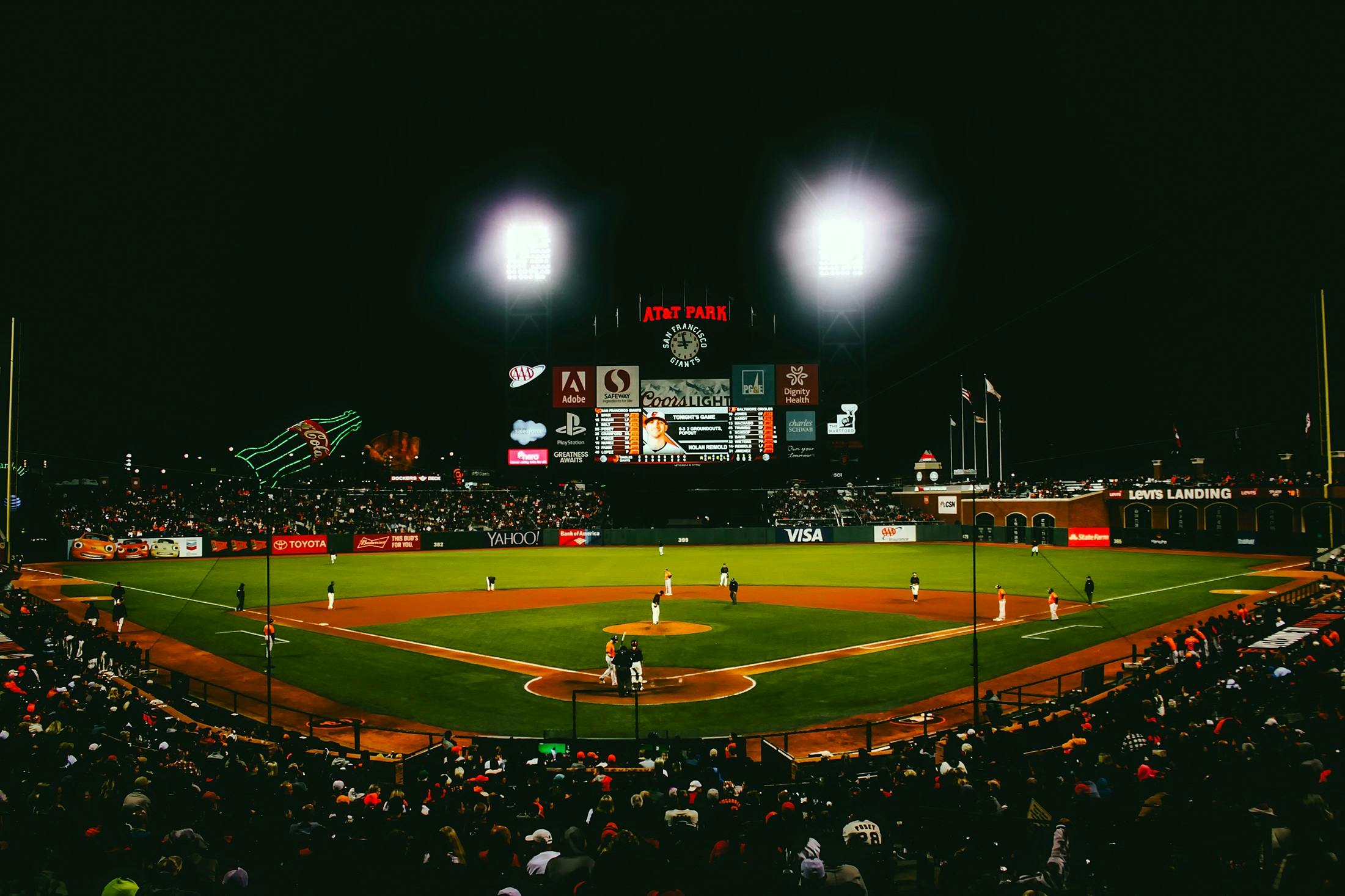 Exciting evening baseball game with fans at AT&T Park stadium under bright lights.